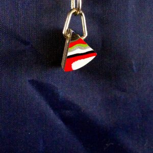 Colorful triangular keychain on dark fabric background.
