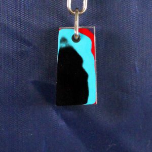 Colorful abstract keychain on blue fabric background.