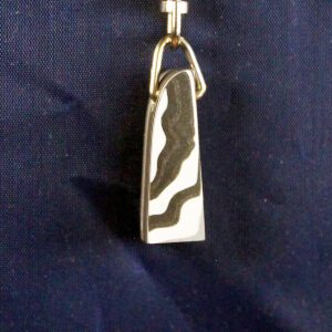 Metallic pendant with wavy design on fabric.