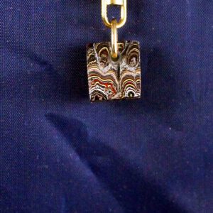 Colorful pendant on a blue fabric background.