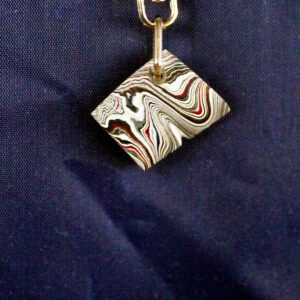 Pendant with swirling black, white, red pattern.