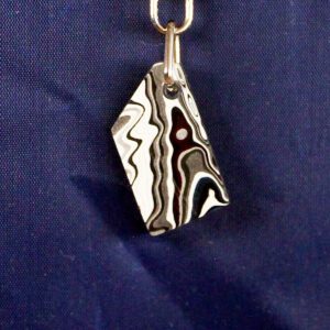 Black and white patterned pendant on chain.