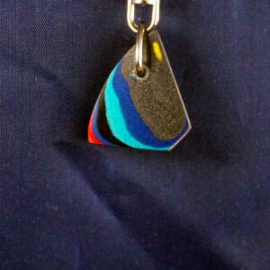 Colorful layered keychain on dark fabric.