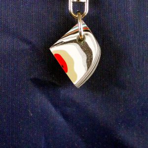 Abstract metal keychain against dark background.