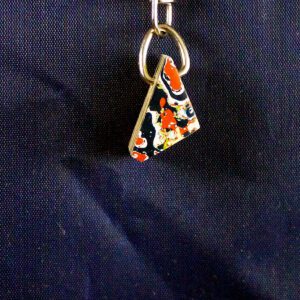 Colorful triangular pendant on dark fabric.