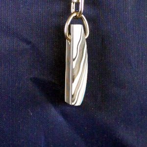 Metal pendant with wavy pattern on fabric.