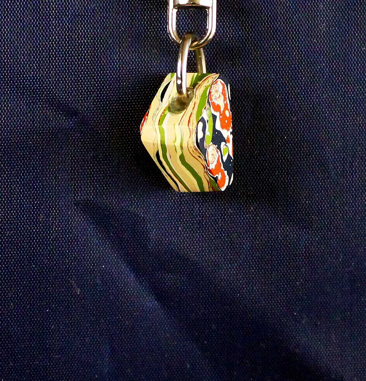 Colorful keychain hanging on dark fabric.
