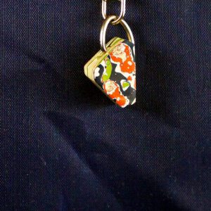 Colorful patterned keychain on dark fabric.