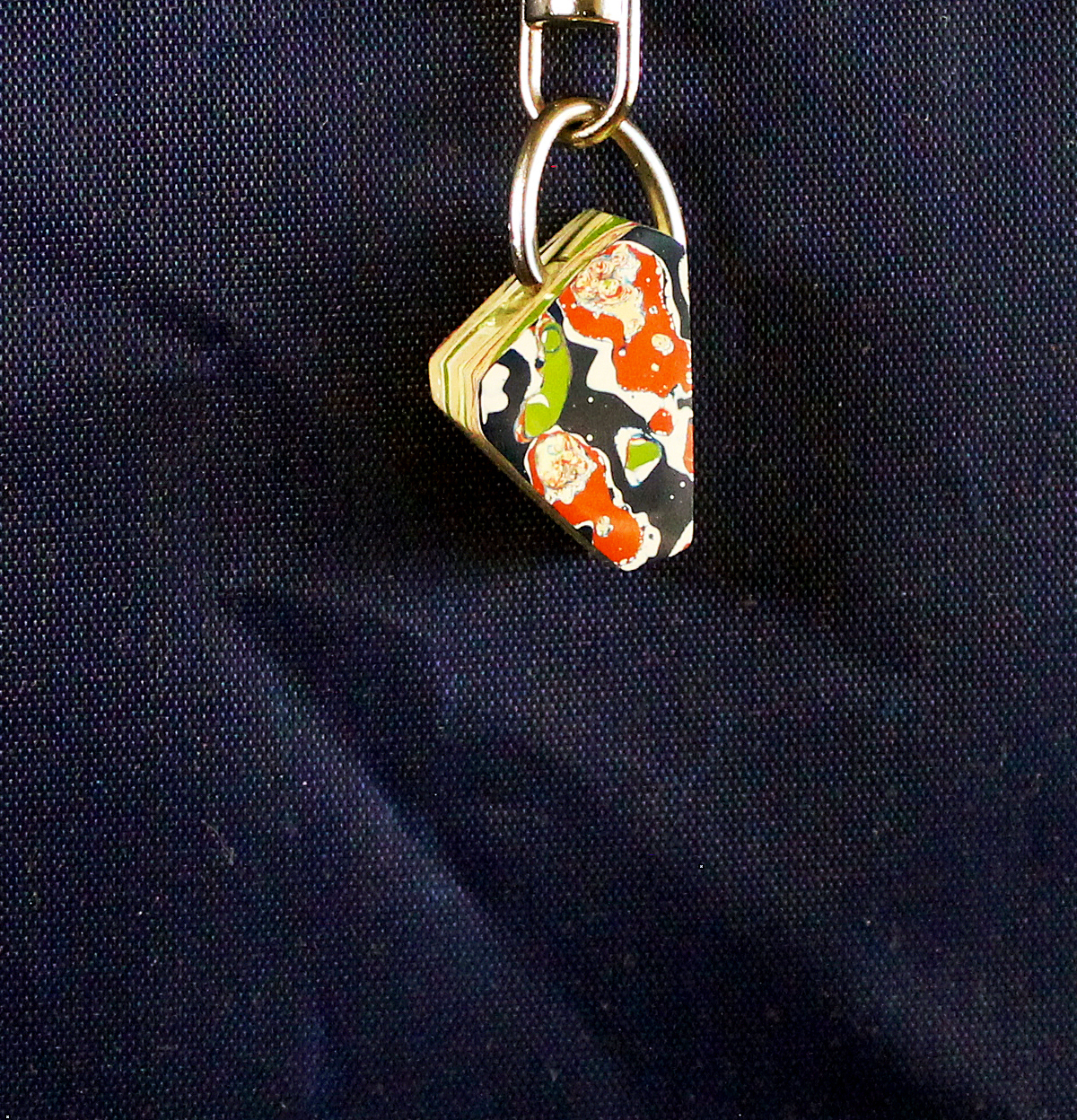 Colorful patterned keychain on dark fabric.