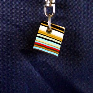 Colorful layered pendant on dark fabric background.
