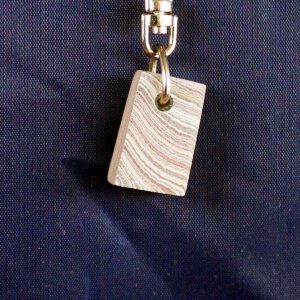 Colorful rectangular keychain on dark fabric.
