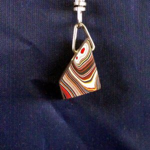 Colorful striped pendant on dark fabric background.