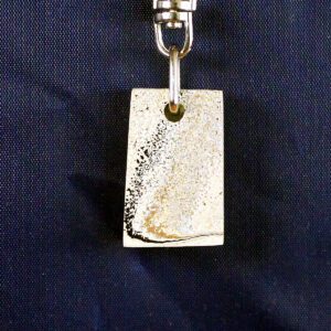 Rectangular metallic keychain on dark background.