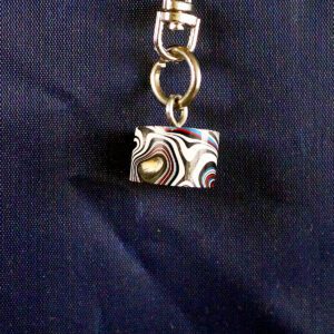 Abstract patterned keychain on dark fabric background.