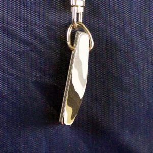 Shiny silver knife keychain on fabric background.