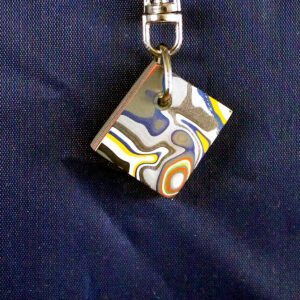 Colorful abstract keychain on dark fabric background.