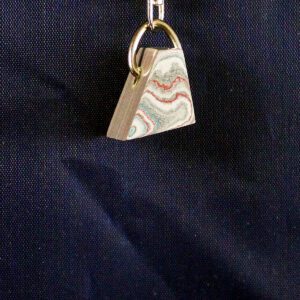 Triangular keychain with colorful layered design.