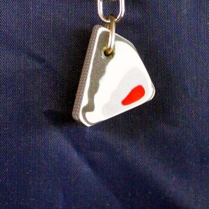 Triangle sushi keychain on dark fabric.