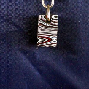 Striped pendant on dark fabric background.