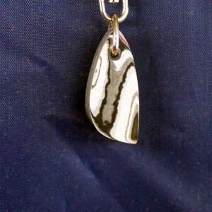 Silver pendant with reflective surface on fabric.