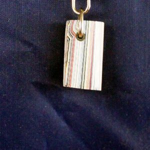 Striped pendant hanging against dark fabric background.