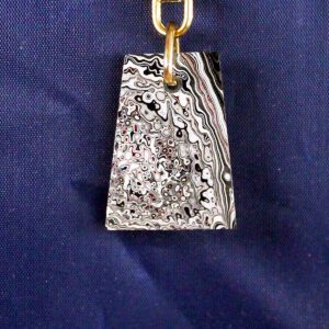 Abstract patterned pendant on blue background.