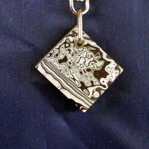 Abstract patterned keychain on blue background.