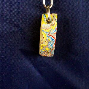 Colorful patterned keychain on blue fabric.