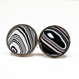 Round cufflinks with abstract black patterns.