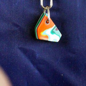 Colorful triangular keychain against blue fabric.