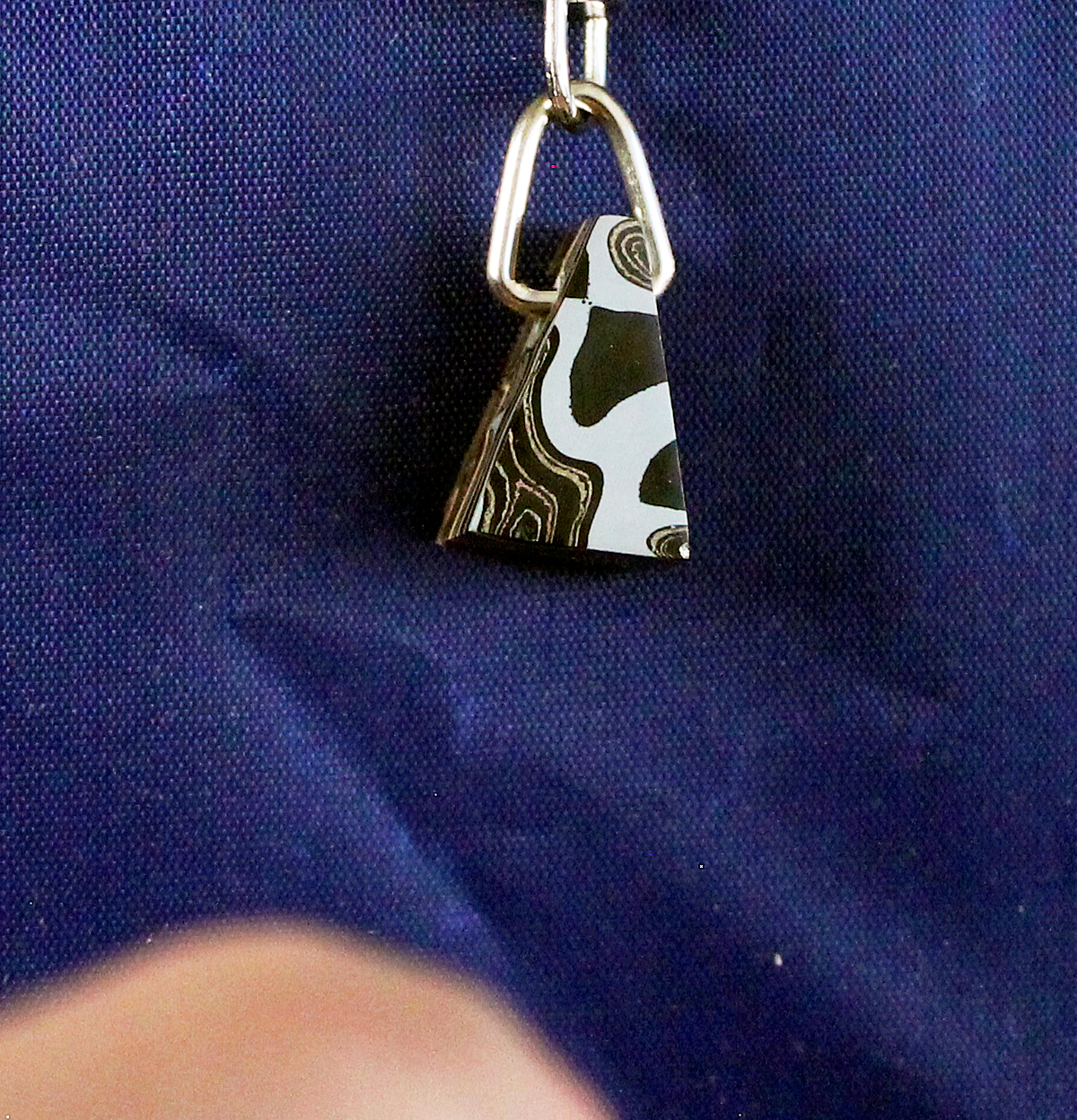 Pendant with abstract pattern on blue fabric.