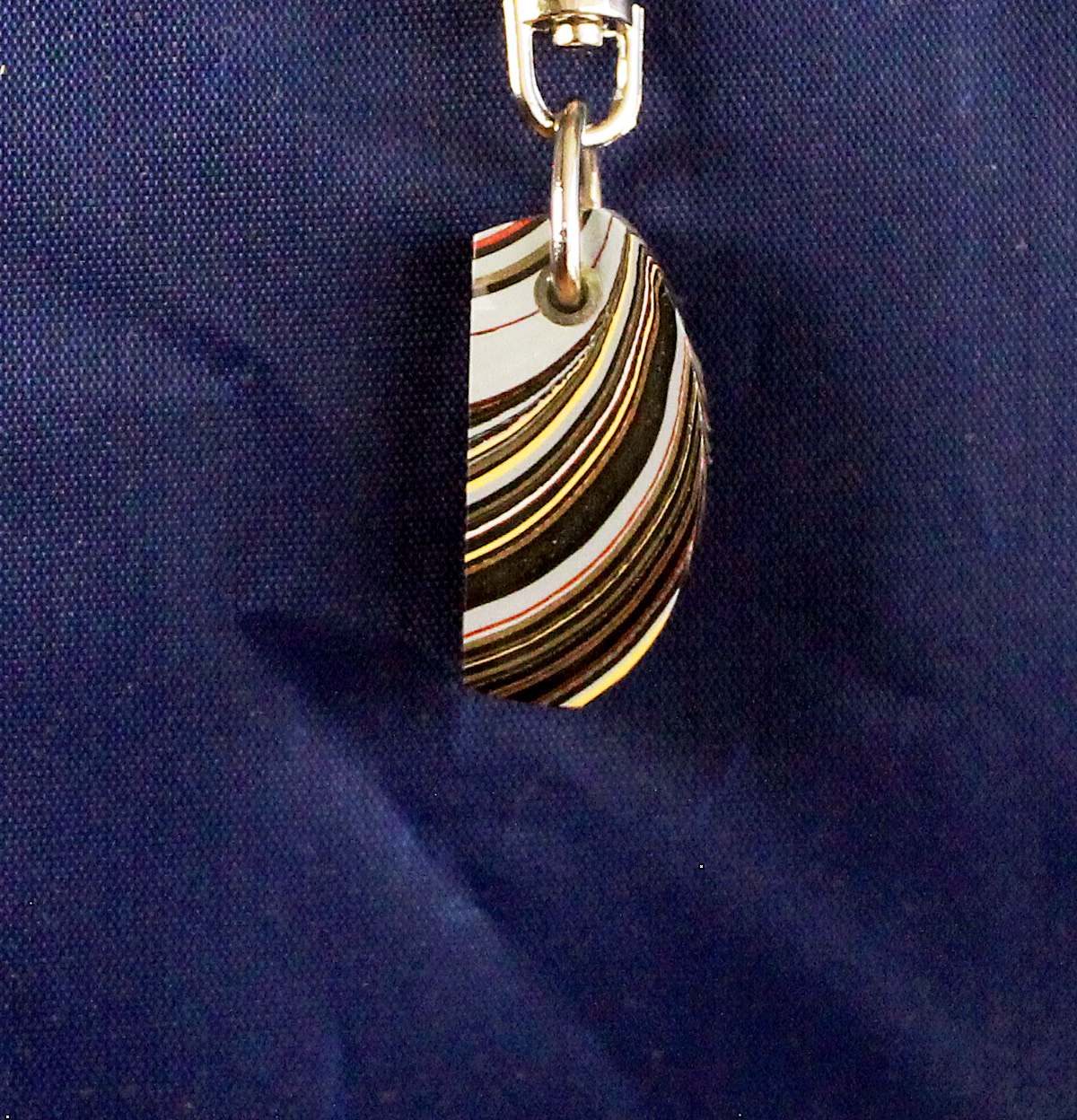 Striped pendant against blue fabric background.
