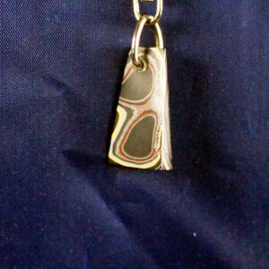 Metallic pendant on a blue fabric background.