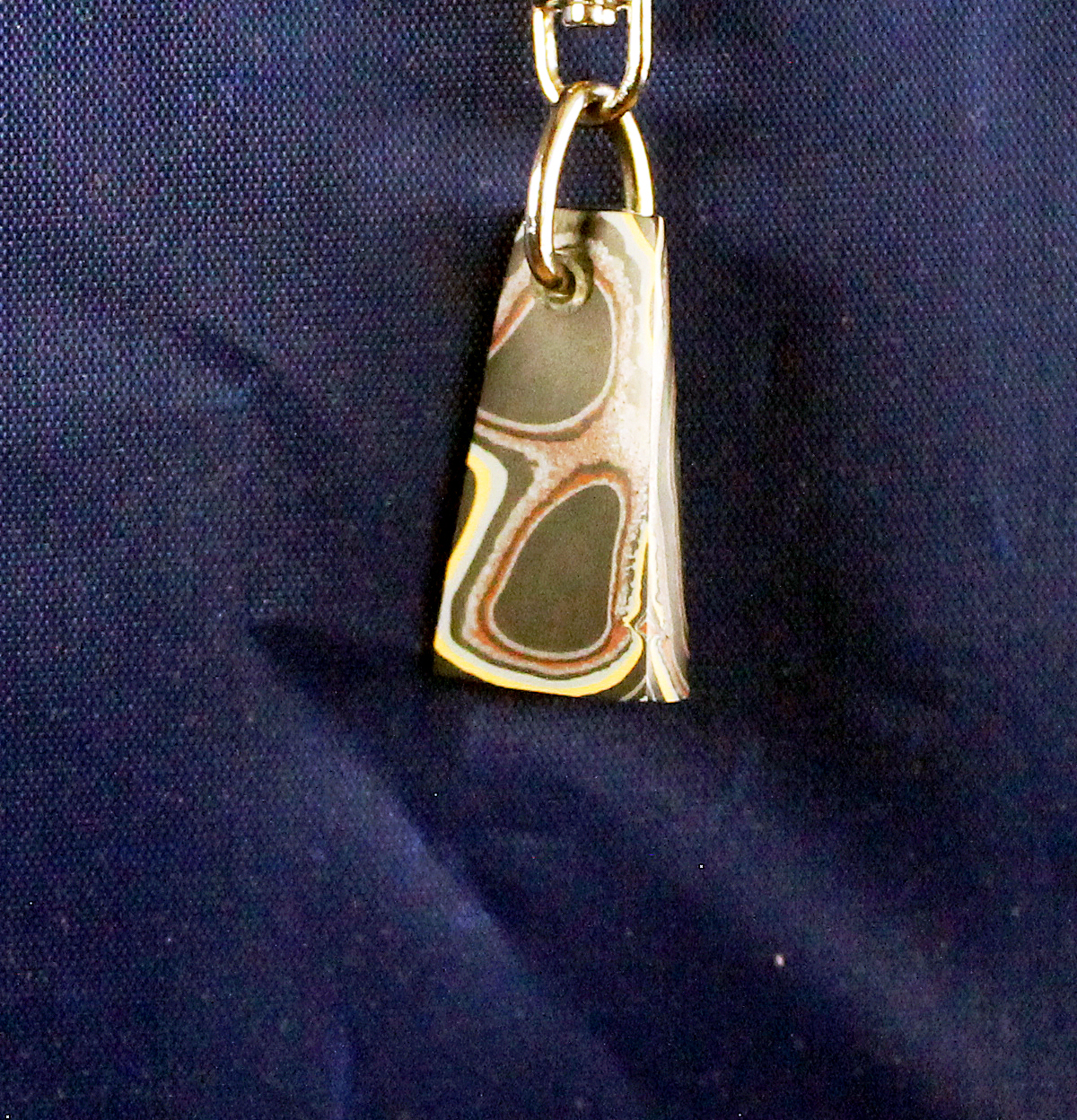 Metallic pendant on a blue fabric background.