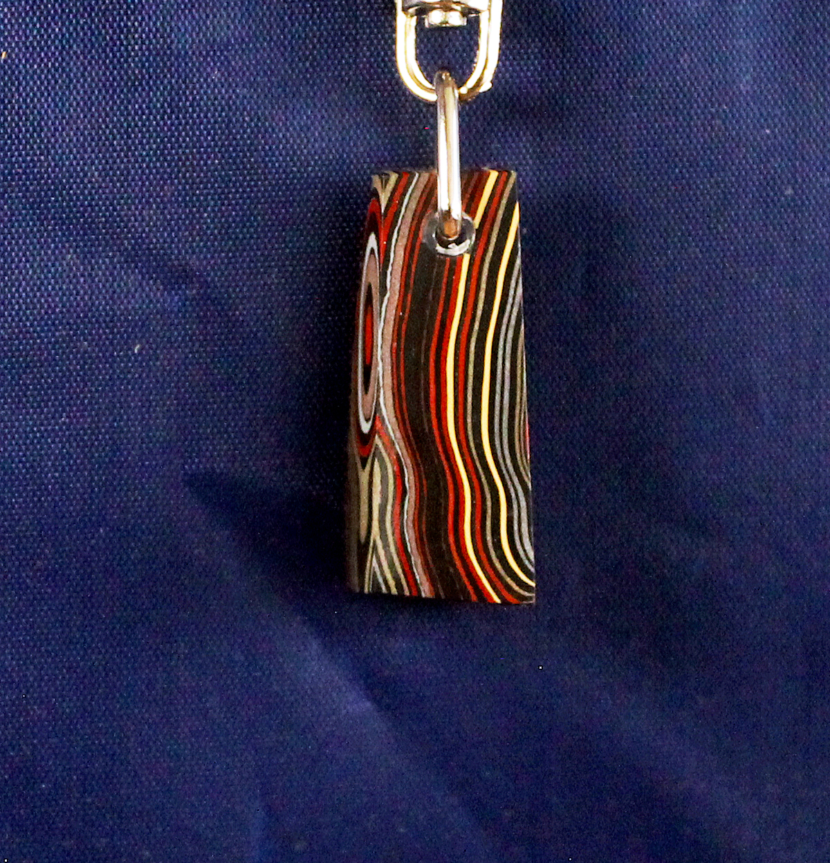 Colorful pendant with swirling patterns on blue.