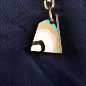 Colorful geometric keychain on dark fabric background.