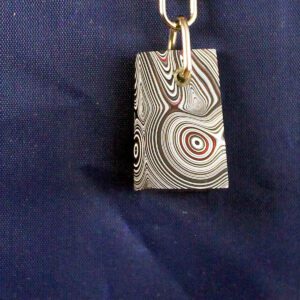 Metal pendant with swirling pattern design.