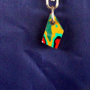 Colorful abstract pendant on blue fabric background.