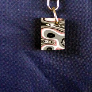 Abstract patterned keychain against dark background.