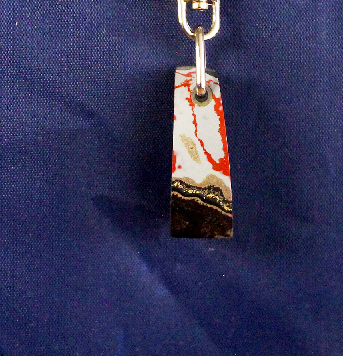Colorful pendant with abstract design on chain.