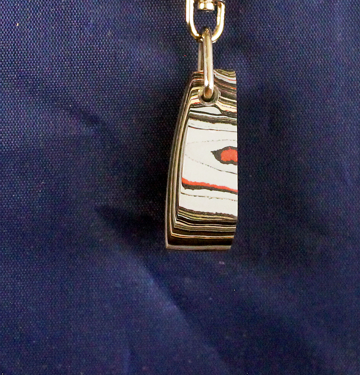 Keychain with layered pendant on navy background.