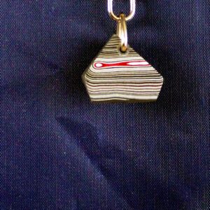 Striped stone pendant with red swirl design.