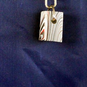 Abstract patterned keychain on dark fabric background.