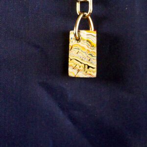 Colorful patterned keychain on dark fabric background.
