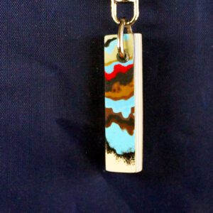 Colorful rectangular pendant against dark background.