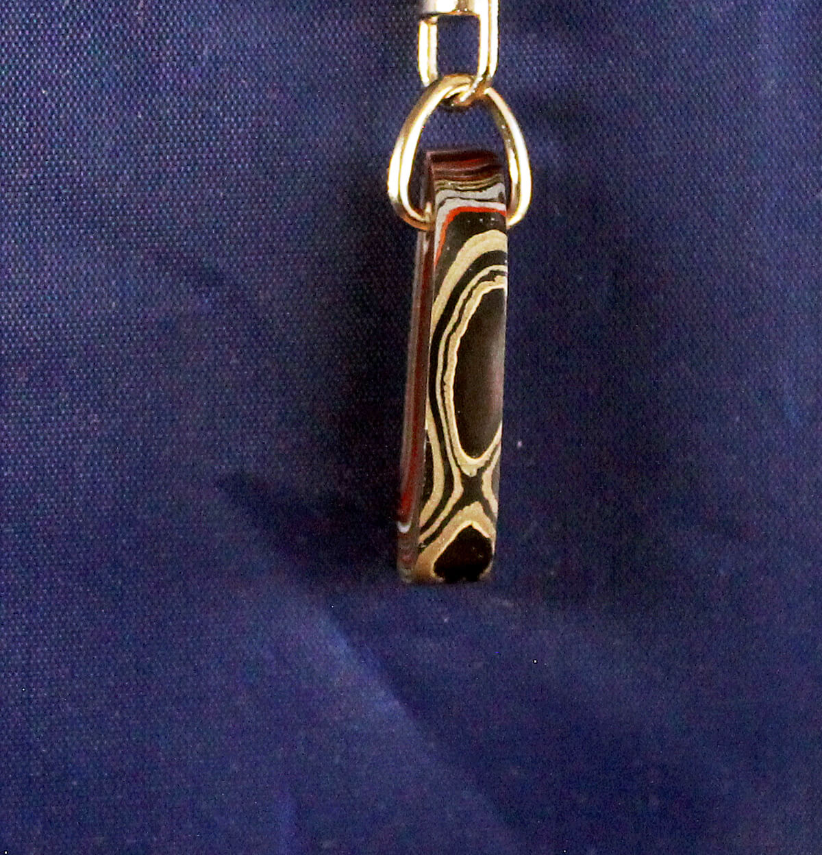 Metallic Damascus keychain against blue background.