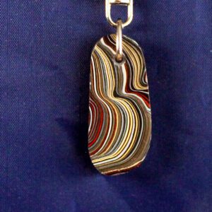 Striped pendant with metal clasp on blue background.