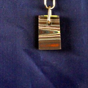 Multicolored pendant on blue fabric background.