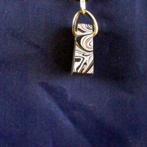 Marbled keychain on dark fabric background.