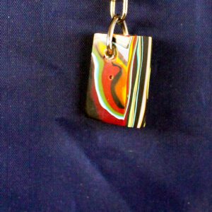 Colorful pendant on a blue fabric background.